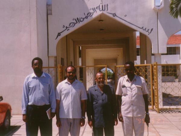 أمام مدرسة الشيخ خليفة بن زايد آل نهيان في مدينا مومباسا ـ كينيا. الكاتب وعلى يساره إبراهيم شيخ إسحاق وعلى يمينه بابكر حسين بركات أحد المدرسين ثم مويني علي خميس نائب مدير المدرسة 26/10/1415هـ ـ 27/3/1995م